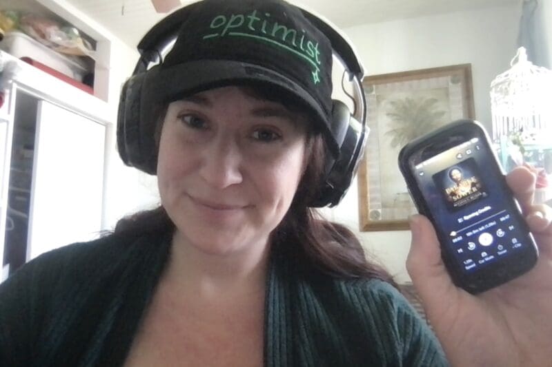 A picture of former Content Specialist Simone Byrd holding her tiny smartphone, the Unihertz Jelly 2, with the Parable of the Sower audiobook pulled up on it